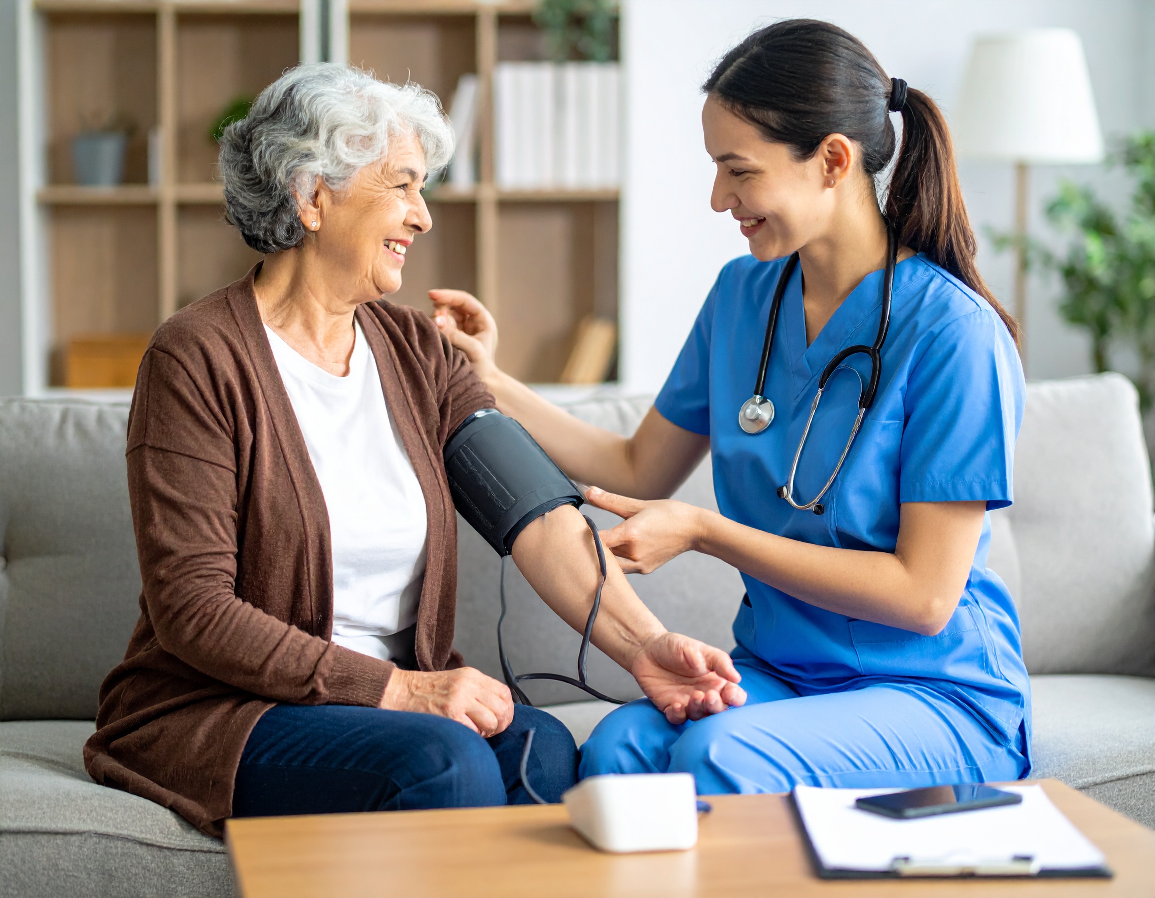 Pflegekraft misst Blutdruck bei älterer Frau in häuslicher Umgebung – professionelle medizinische Versorgung mit Herz und Kompetenz.</p>
<p>