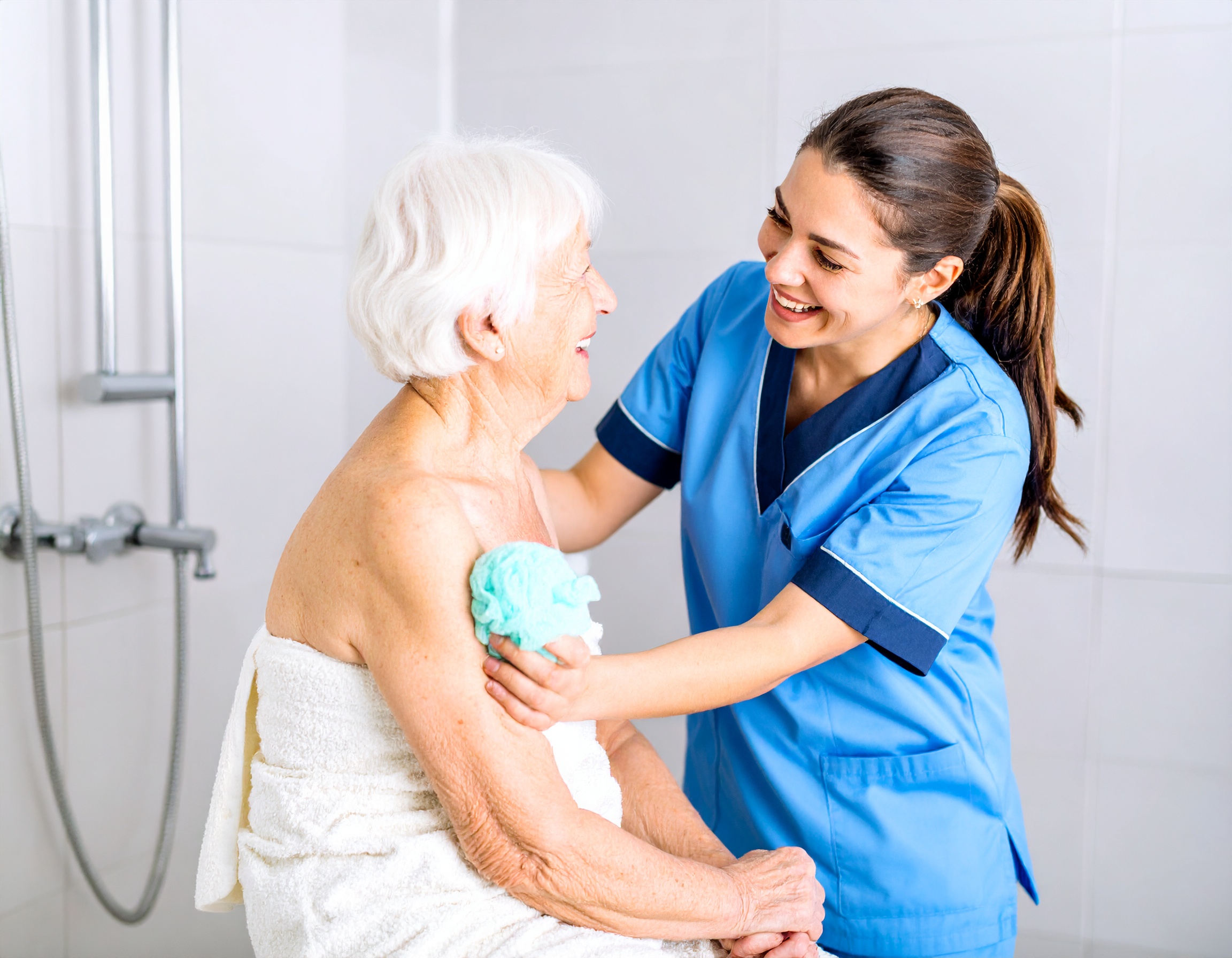 Pflegekraft unterstützt ältere Frau beim Waschen im Badezimmer – würdevolle Grundpflege in sicherer, hygienischer Umgebung.</p>
<p>